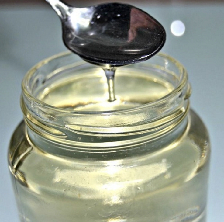 Jarabe de glucosa en frasco de vidrio tomada por una cuchara para hacer notar la consistencia