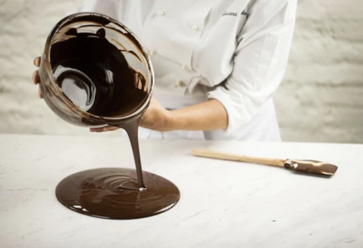 Chef poniendo chocolate fundido en una mesa de mármol